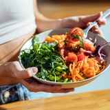 Eine Frau hält eien Teller mit Gemüse und Salat in der Hand