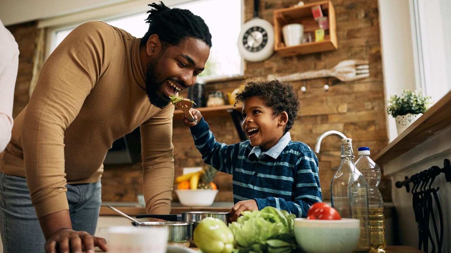Behauptung: Kinder können sich ohne Fleisch nicht gesund entwickeln Ein Kind füttert seinen Papa mit einer Gabel, beide lachen