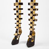 "Ein Aufeinandertreffen von Dschungel und Hofstaat", so beschrieb einmal die "New York Times" die Designs von Gianni Versace: leuchtende Farben einerseits und tiefes Schwarz andererseits, Riemen, Schnallen, metallische Akzente, der goldene Medusenkopf in seinem Logo sind Teil seiner Markenästhetik.   Gold, Riemen, Medusaköpfe – das Modell aus dem Jahr 1992 vereint alle Elemente, die für den Versace-Still so kennzeichnend sind.   Gianni Versace designte bis zu seinem gewaltsamen Tod im Jahr 1997. Dann übernahm seine Schwester Donatella die Leitung des Labels. Sie hatte bereits häufig mit ihrem Bruder zusammengearbeitet und präsentierte nur zwölf Wochen nach dessen Tod ihre erste Kollektion. Für ihren eigenen Stil griff sie Aspekte seiner Designphilosophie auf und entwickelte die Versace-Ästhetik weiter. "Manche meinten, Giannis Mode sei vulgär ... aber Frauen lieben sie nun mal, nicht weil sie Haut zeigte, sondern weil er die Frauen stark machte. Er sagte ihnen, sie sollten keine Angst vor ihrer Sexualität haben", erklärte Donatella. 