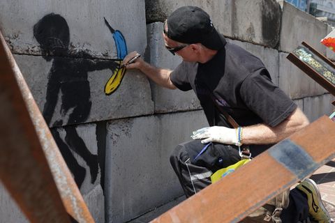 Thomas Baumgärtel sprüht eine Banane neben ein Werk von Banksy