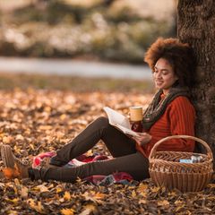 Frau liest im Herbst ein Buch