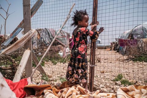 Eines der Kinder von Yurub Abdi Jama steht neben einem Zaun an ihrem Haus in einer informellen Siedlung von Binnenvertriebenen