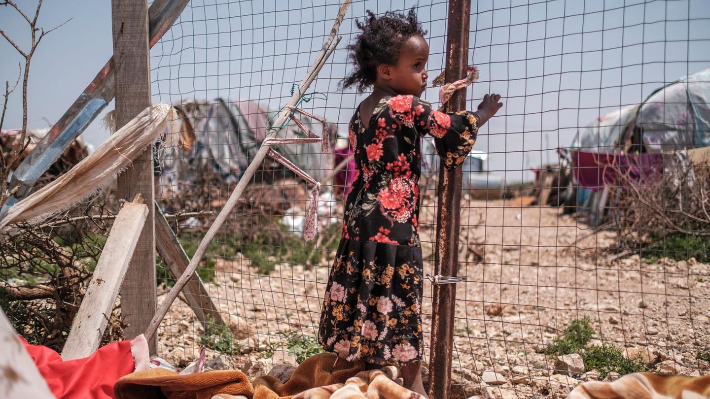 Eines der Kinder von Yurub Abdi Jama steht neben einem Zaun an ihrem Haus in einer informellen Siedlung von Binnenvertriebenen