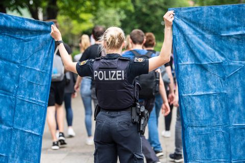Polizistin in Bremerhaven schirmt Schüler:innen mit Plane ab