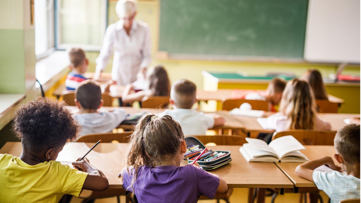 Grundschulkinder sitzen in Schule und erledigen Aufgaben