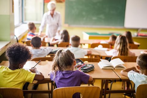 Grundschulkinder sitzen in Schule und erledigen Aufgaben