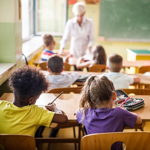 Grundschulkinder sitzen in Schule und erledigen Aufgaben