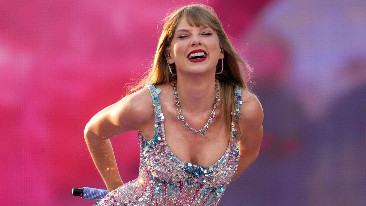 Taylor Swift steht lachend auf einer Bühne