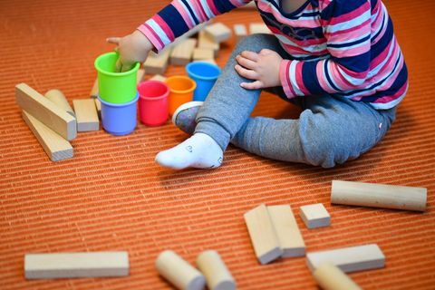 Ein Mädchen spielt in einer Kita mit bunten Bechern und Bauklötzen
