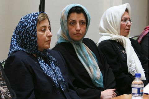 Drei Frauen, die ein Tuch tragen, sitzen nebeneinander