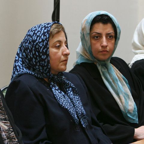 Drei Frauen, die ein Tuch tragen, sitzen nebeneinander