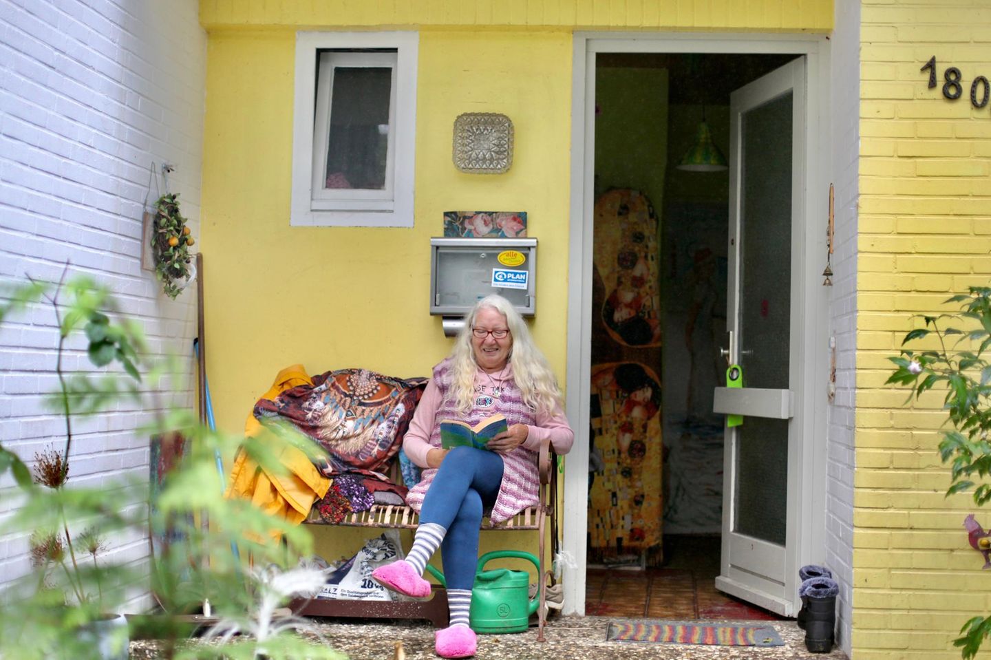 Elke Renate Kruse sitzt vor ihrem Haus und liest ein Buch