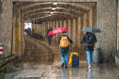 Passanten mit Regenschirmen sind bei Starkregen unterwegs