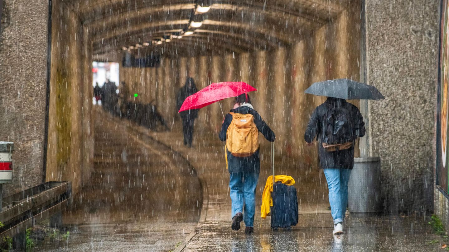 Passanten mit Regenschirmen sind bei Starkregen unterwegs