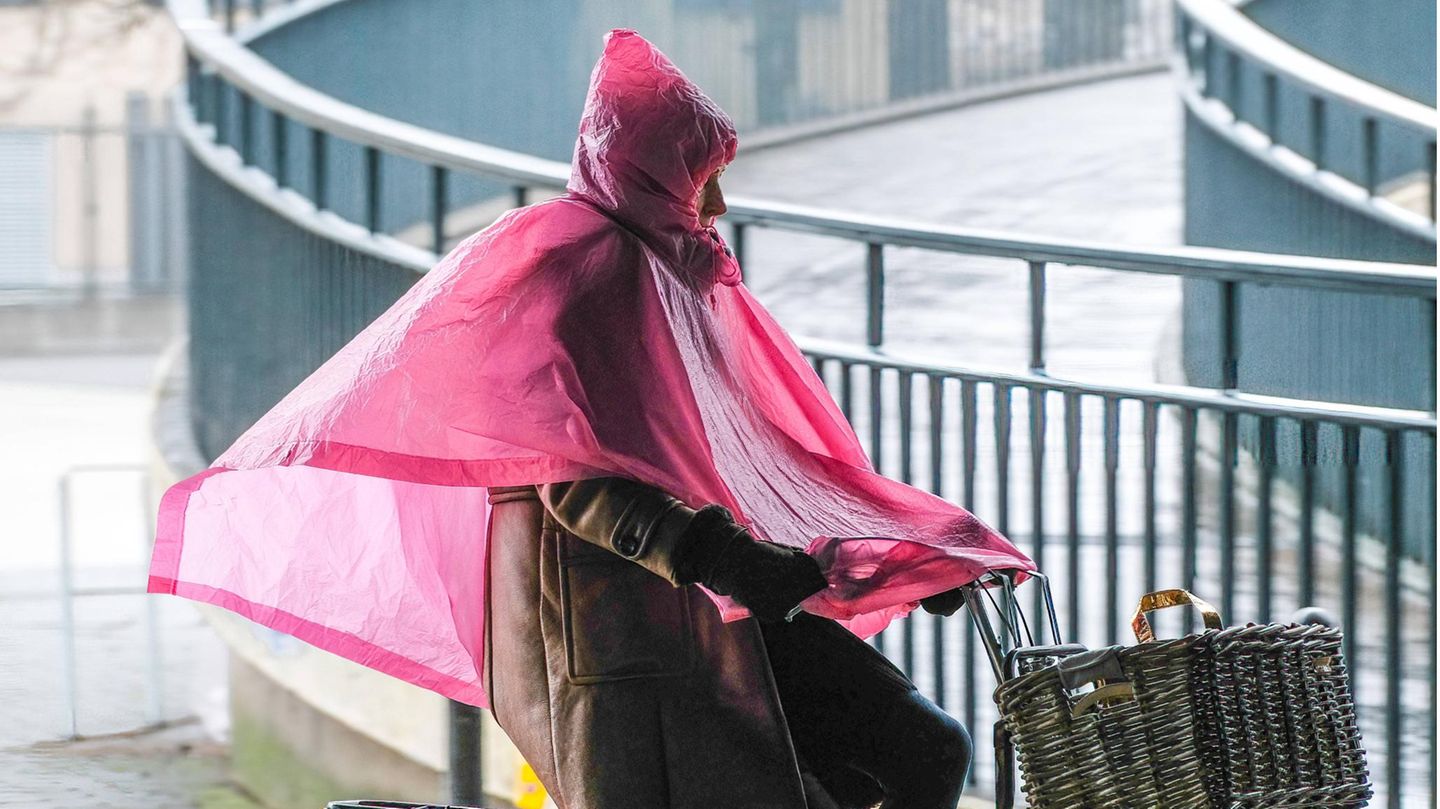Mensch auf Fahrrad in rosa Regenponcho
