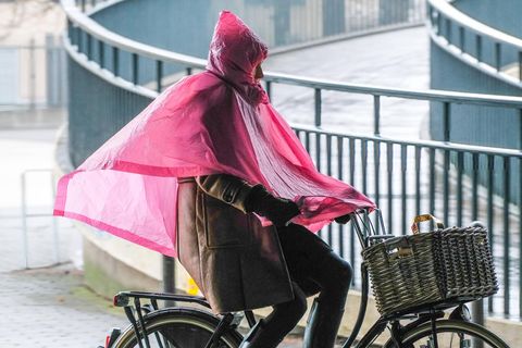 Mensch auf Fahrrad in rosa Regenponcho