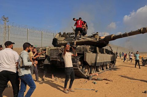 Palästinenser umringen einen beschädigten israelischen Kampfpanzer