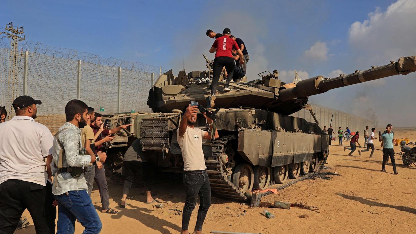Palästinenser umringen einen beschädigten israelischen Kampfpanzer