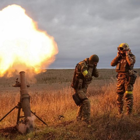 Eine Waffe feuert ab und zwei Soldaten stehen daneben und halten sich die Ohren zu