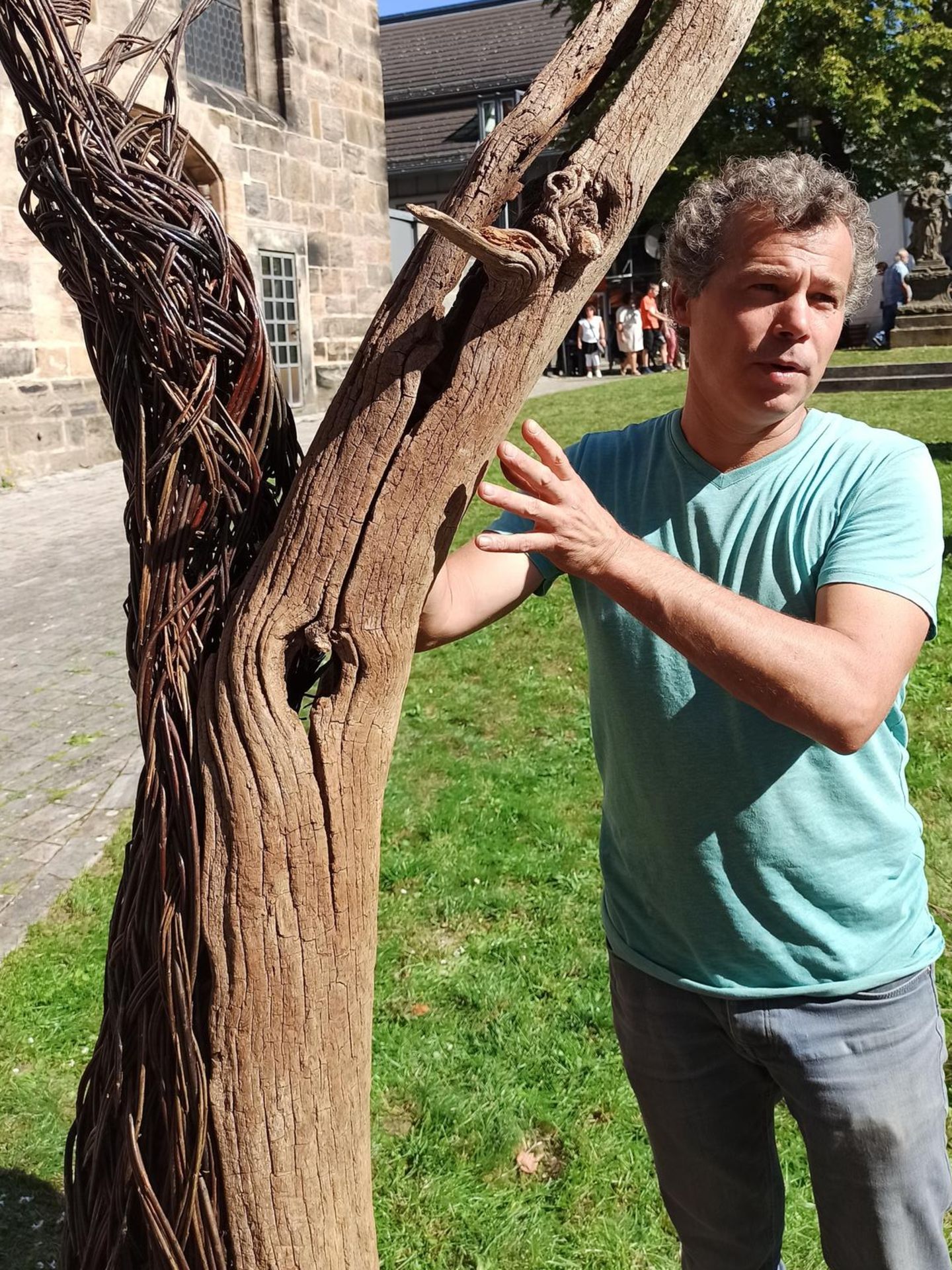 Mann umarmt Baum mit Flechtwerk