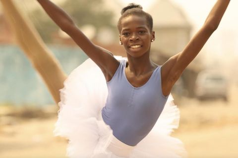 schwarzes Mädchen in einem Ballet-Tutu in tanzender Pose, im Hintegrund Slums Afrikas