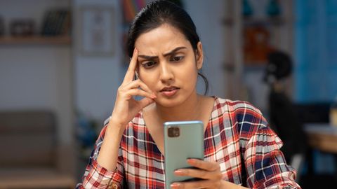 Eine Frau guckt mit angespannten Gesicht auf ihr Smartphone