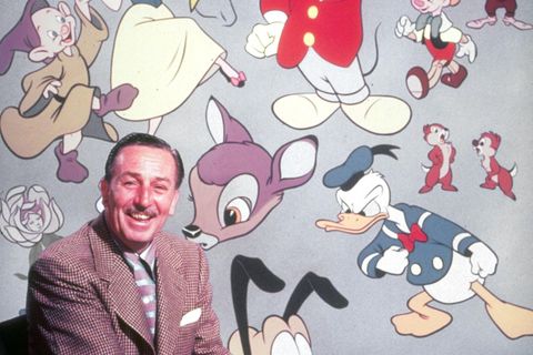 Walt Disney sitzt vor einer Wand mit den berühmtesten Disney-Figuren