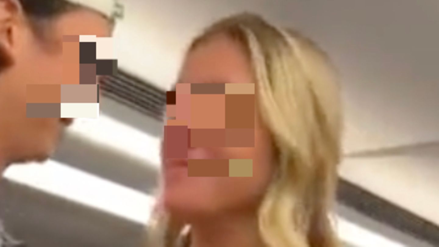 Eine möglicherweise betrunkene Frau steht grinsend in einem Zugabteil