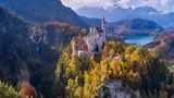 Blick auf Schloss Neuschwantsein – eingebettet in die Herbslandschaft vor Bäumen und Bergen