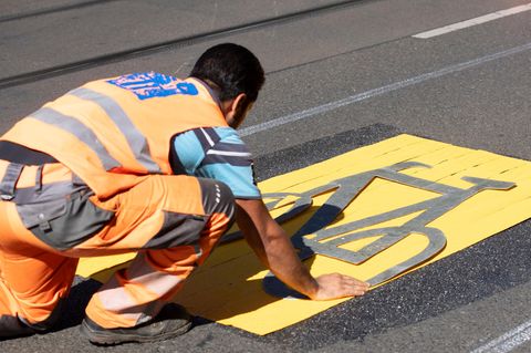 Ein Bauarbeiter bereitet die Markierung einer Fahrradspur im Straßenverkehr vor