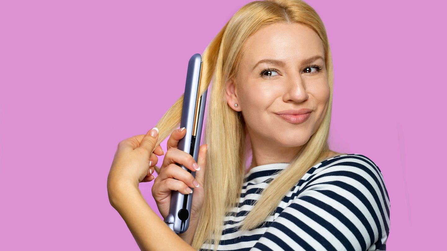 Frau mit Glätteisen beim Haarestylen