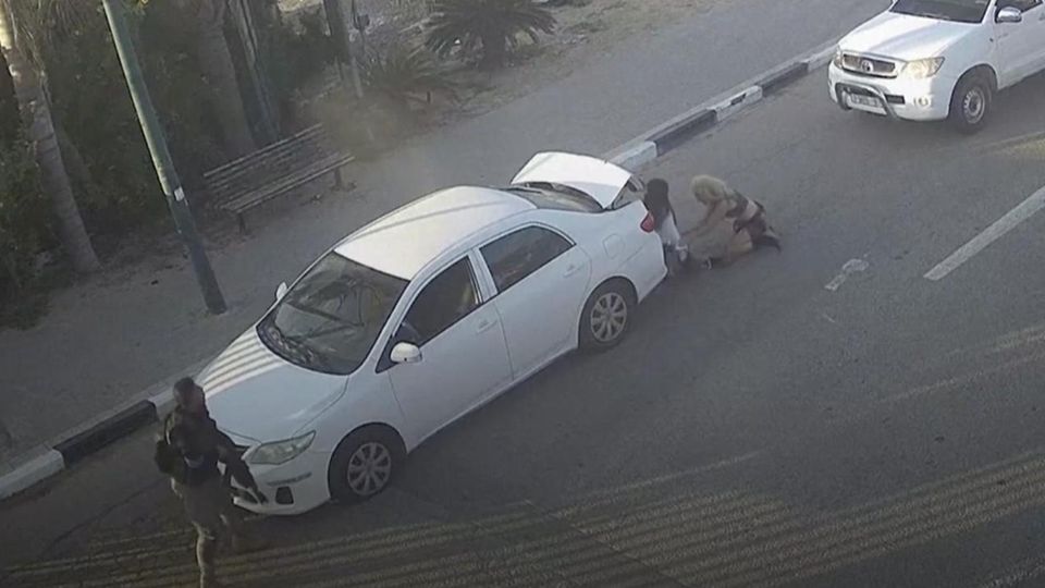 Zwei Frauen verstecken sich hinter Auto, links israelischer Polizist Zwei Frauen verstecken sich hinter Auto, links israelischer Polizist