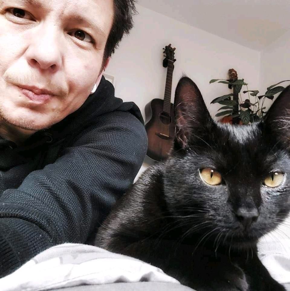 Mann und schwarzer Kater machen ein Selfie