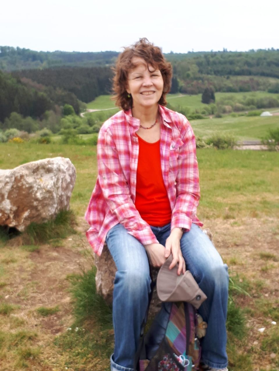 Eine Frau sitzt auf einem Stein im Grünen