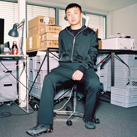 Carl Pei, ein junger Mann, sitzt auf einem Schreibtischstuhl, hinter ihm Kartons