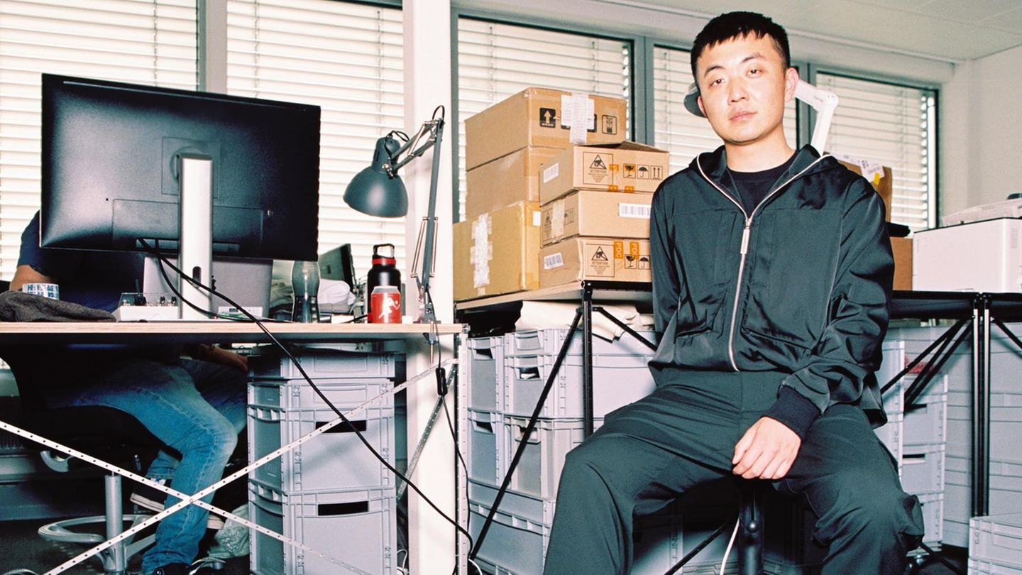 Carl Pei, ein junger Mann, sitzt auf einem Schreibtischstuhl, hinter ihm Kartons