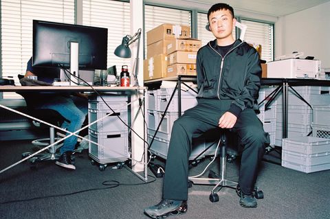 Carl Pei, ein junger Mann, sitzt auf einem Schreibtischstuhl, hinter ihm Kartons