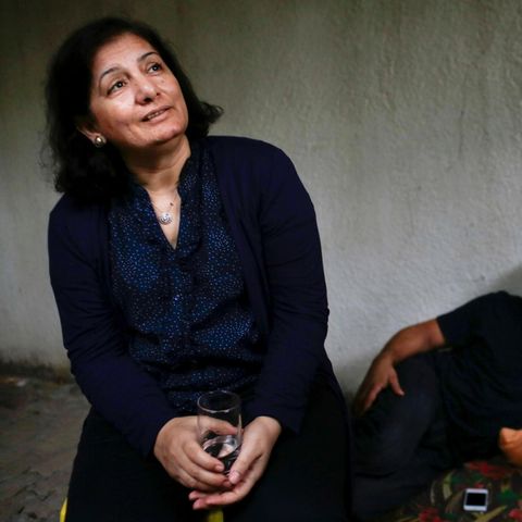 Andalib Adwan sitzt in einem Raum mit zwei Menschen im Hintergrund