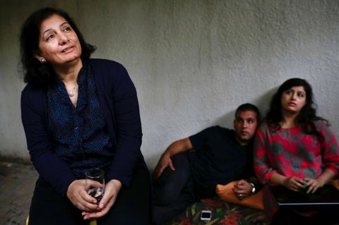 Andalib Adwan sitzt in einem Raum mit zwei Menschen im Hintergrund