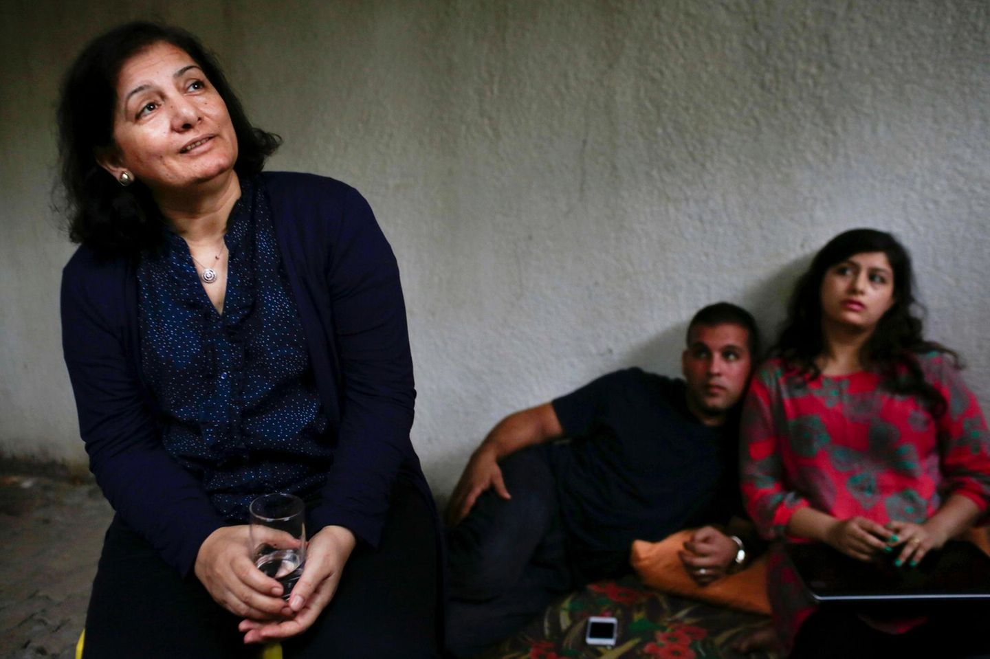 Gaza Andalib Adwan sitzt in einem Raum mit zwei Menschen im Hintergrund