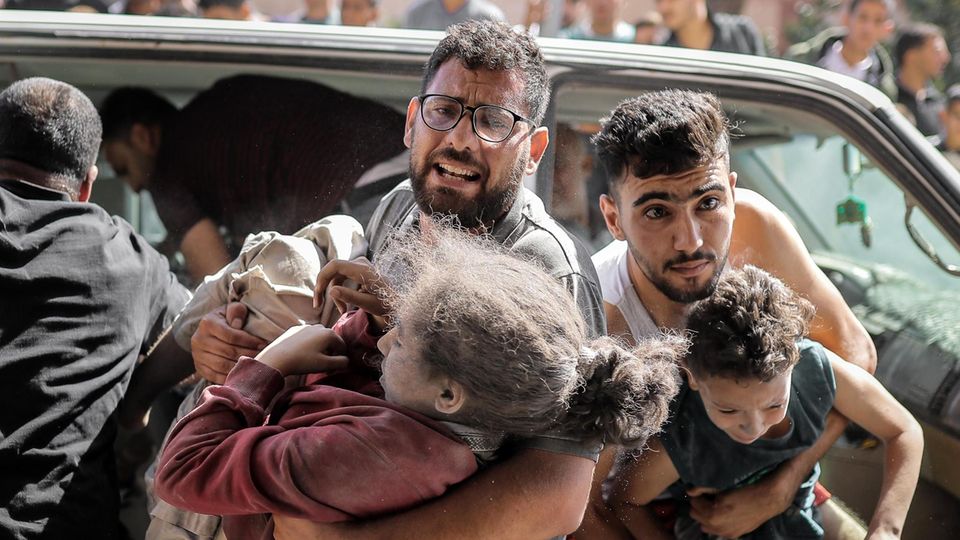Zwei Männer tragen Kinder aus einem Auto