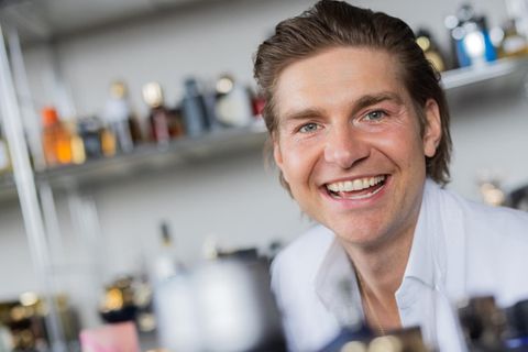 Parfum-Blogger Jeremy Fragrance, 34, im weißen Anzug vor einem Regal mit Düften