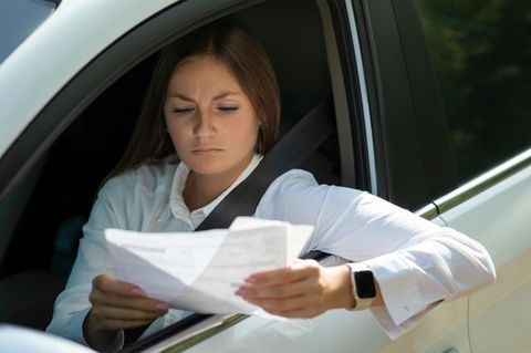Frau im Auto bekommt Strafzettel Knöllchen