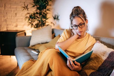 Eine Frau liest auf dem Sofa ein Buch