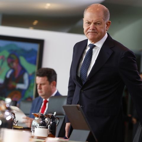 Kanzler Olaf Scholz bei einer Kabinettssitzung. Ein Mann in Anzug und Krawatte steht an einem Tisch