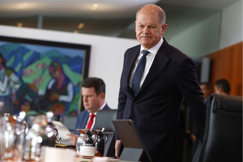 Kanzler Olaf Scholz bei einer Kabinettssitzung. Ein Mann in Anzug und Krawatte steht an einem Tisch