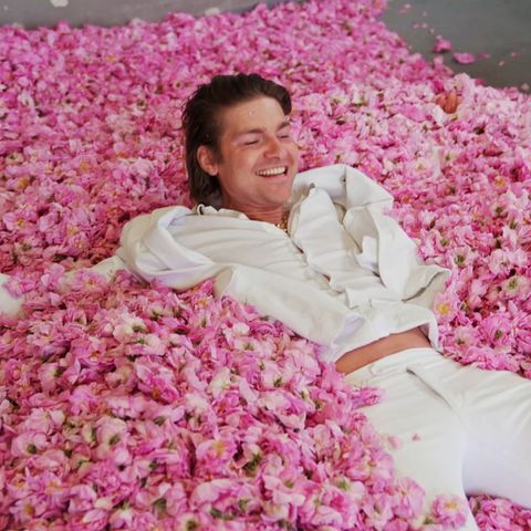 Duft-Influencer Jeremy Fragrance liegt auf einem Haufen aus Rosenblättern