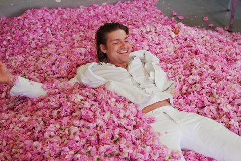 Duft-Influencer Jeremy Fragrance liegt auf einem Haufen aus Rosenblättern
