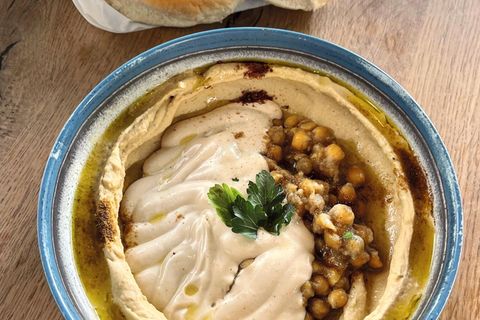 Hummus Kanaan  Oz und Jalil: Hummus kann als Dip zu unzähligen Gerichten serviert werden, auch als Brotaufstrich oder einfach zu Gemüsesticks ist er ein leckerer Snack.      Für 6 Personen  Zutaten:  300 g getrocknete Kichererbsen, 1⁄4 TL Natron, 50 ml eiskaltes Wasser, 1 TL Salz, 140 g Tahini, Saft von 1 großen Zitrone, 1⁄2 TL Zucker, Olivenöl zum Garnieren  Zubereitung:  » Die Kichererbsen über Nacht in Wasser einweichen. Am nächsten Tag in ein Sieb abgießen, gut abspülen und mit reichlich kaltem Wasser und Natron in einen großen Topf geben und aufkochen, dann ca. 1,5 Stunden kochen lassen. Sie sollten so weich sein, dass sie sich leicht zwischen zwei Fingern zerdrücken lassen.  » Den dabei entstehenden Schaum und die sich an der Oberfläche absetzenden Kichererbsenschalen mit einem großen Servierlöffel oder Schaumlöffel abschöpfen.  » In ein Sieb abgießen und das Kochwasser auffangen. Die gekochten Kichererbsen unter fließendem Wasser abspülen, um Natronreste zu entfernen.  » Die Kichererbsen in eine Küchenmaschine geben und das eiskalte Wasser zufügen. So lange pürieren, bis eine glatte, cremige Textur entstanden ist. Bei Bedarf zusätzlich etwas Kochwasser zugeben.  » Die restlichen Zutaten zufügen und weiterpürieren, bis die gewünschte Konsistenz erreicht ist. Weiteres Kochwasser zufügen, falls nötig.  » In eine Servierschale geben und mit etwas Olivenöl beträufeln. Am besten warm oder direkt nach dem Abkühlen genießen.