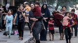 Frauen und Kinder fliehen eine Straße in Gaza-Stadt entlang. Die Angst ist ihnen ins Gesicht geschrieben.